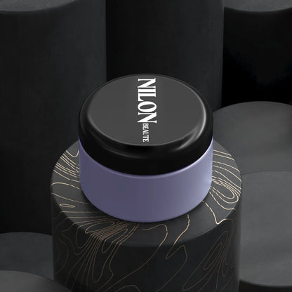 Exfoliating clay mask for sensitive skin in black and lavender packaging on textured background.
